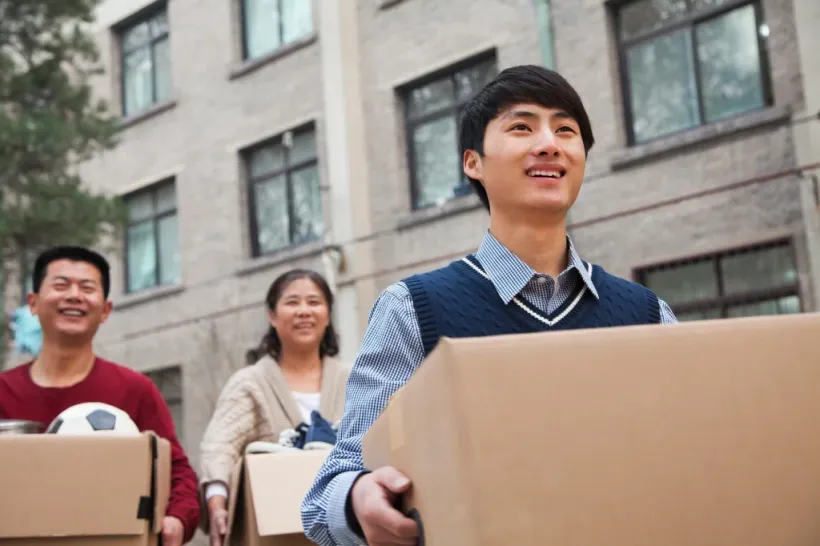 Student transferring and moving out to a new school, carrying belongings and leaving campus.
