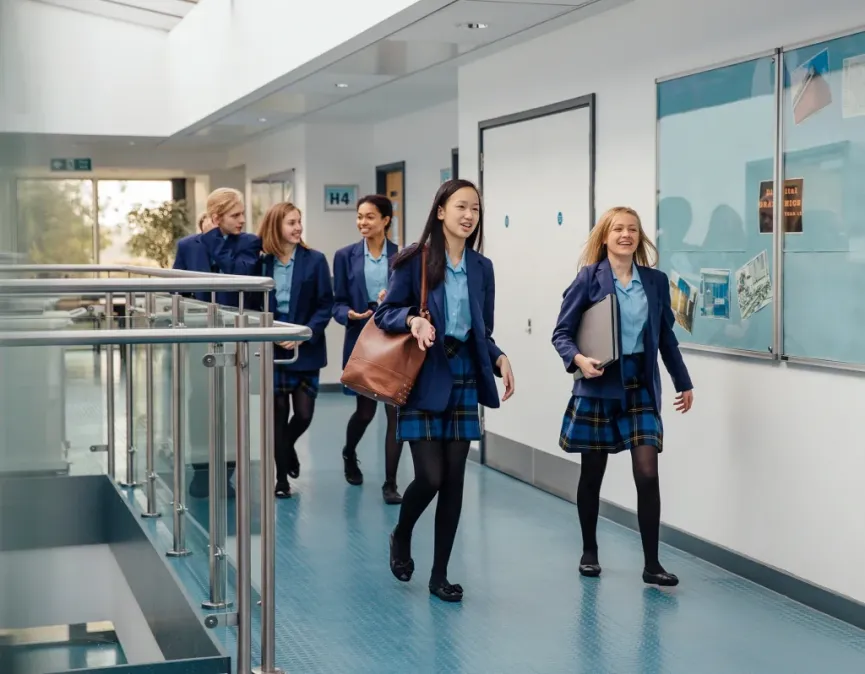 Diverse students in school uniforms smiling in a bright hallway, symbolizing IvyWise’s WiseStart Middle School program