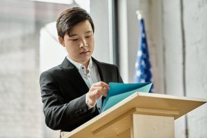 Student at podium reviewing notes for a speech or presentation.