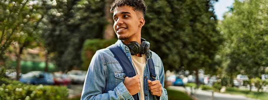 Smiling student holding books on a college campus, ready for academic success.
