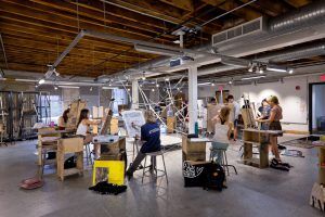 Students drawing in a bright, open art studio, developing college portfolio pieces.