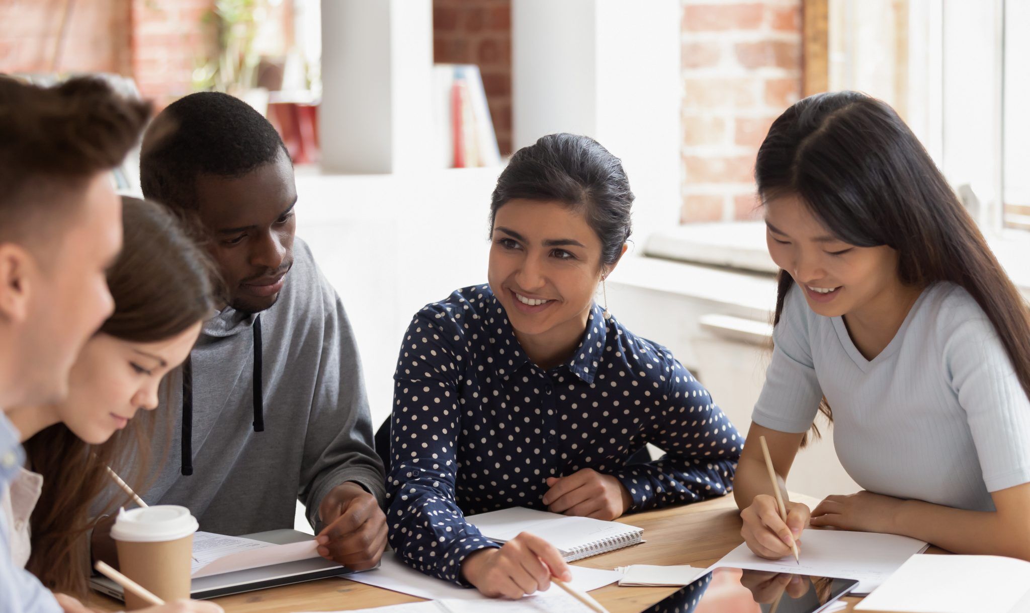 Focused multi national students sitting at desk studying together