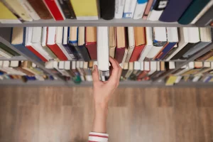 hand reaching for a book on library shelf