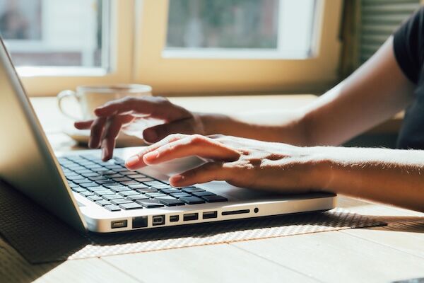 young girl works on a computer at the window