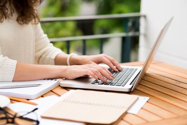 side view of young woman's hands typing on laptop
