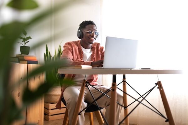 smiling student with headphones on laptop