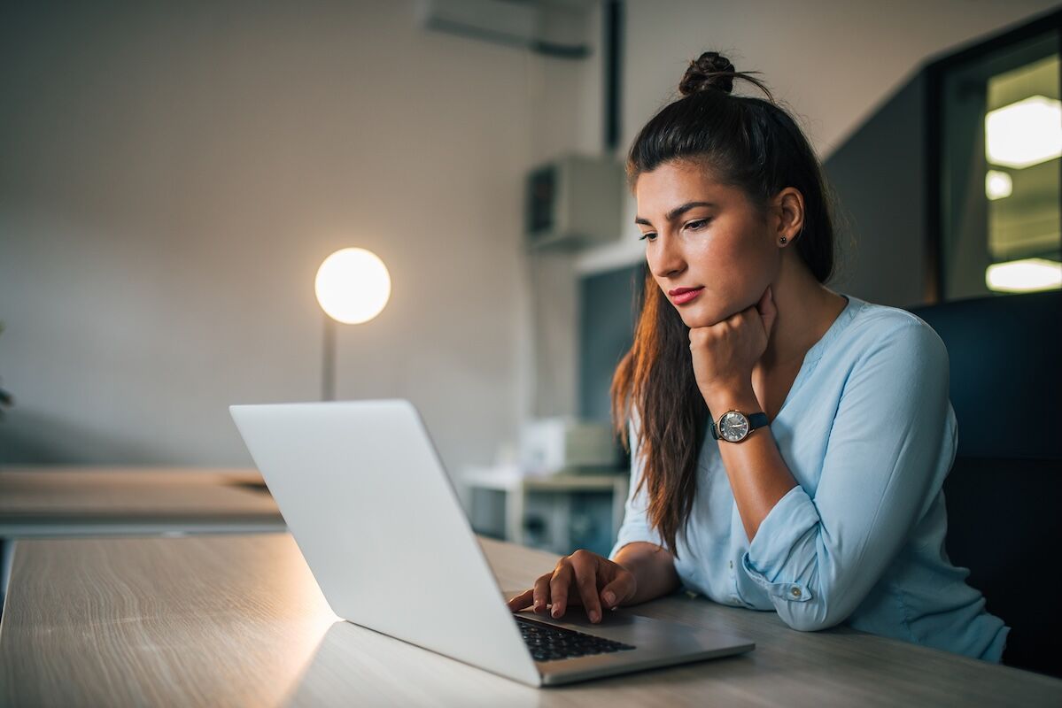 Beautiful casual student using laptop indoors.