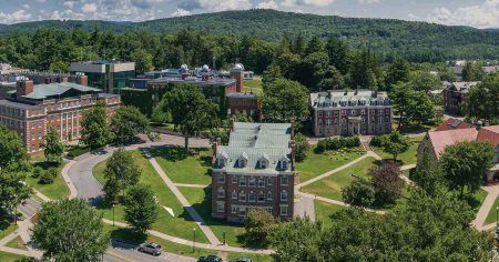 Top-down shot of a traditional collegiate campus featuring red-brick buildings and lush quad lawns.